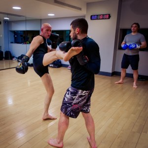 Coach Phil Whyte throws a right kick to a students gloves
