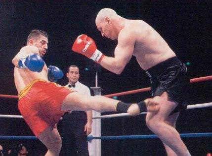 Andy Hug throws a right leg kick at Mike Bernardo's thigh 

